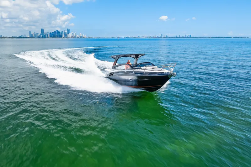  Yacht Photos Pics 2025 Hanover 305 boat cruising on blue ocean with city skyline in background.