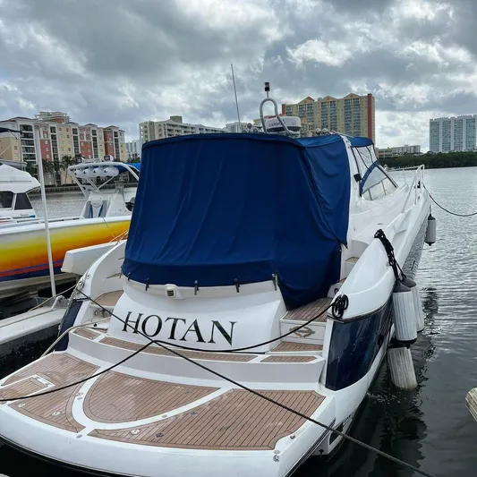  Yacht Photos Pics 2003 Sunseeker Portofino 46 yacht docked, covered with blue tarp, cityscape in background.