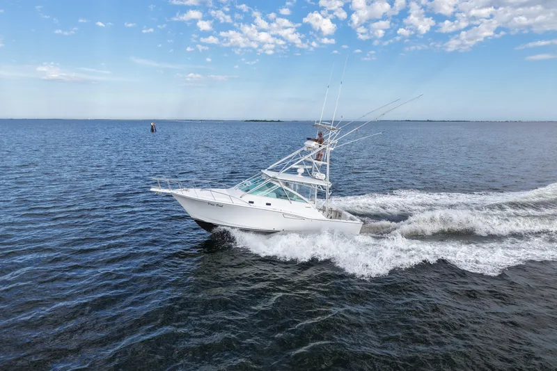Done Deal Yacht Photos Pics 2001 Cabo 35 Express boat cruising on open water under a clear sky.