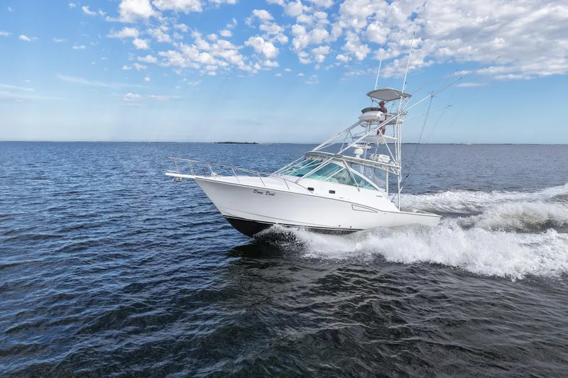 Done Deal Yacht Photos Pics 2001 Cabo 35 Express boat cruising on open water under a partly cloudy sky.