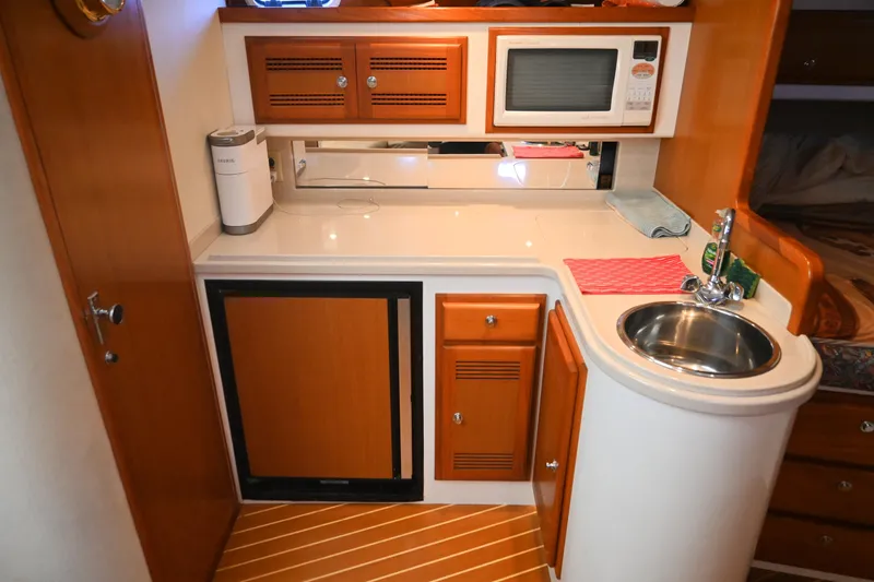 Done Deal Yacht Photos Pics 2001 Cabo 35 Express yacht kitchenette with sink, microwave, and wooden cabinetry.