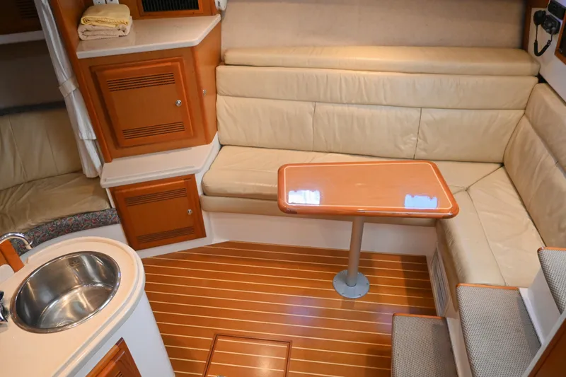 Done Deal Yacht Photos Pics 2001 Cabo 35 Express interior with leather seating, wooden table, and compact kitchenette.