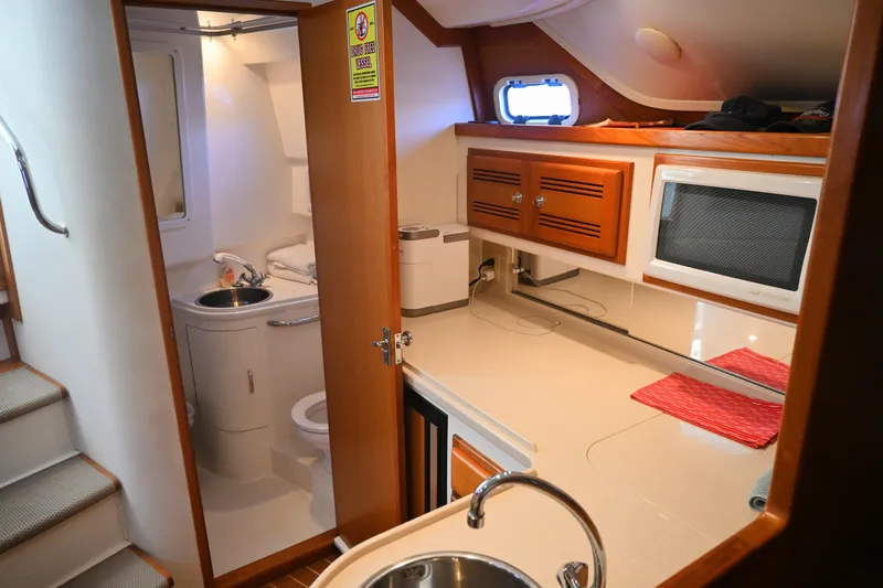 Done Deal Yacht Photos Pics 2001 Cabo 35 Express interior with kitchenette, sink, microwave, and bathroom.