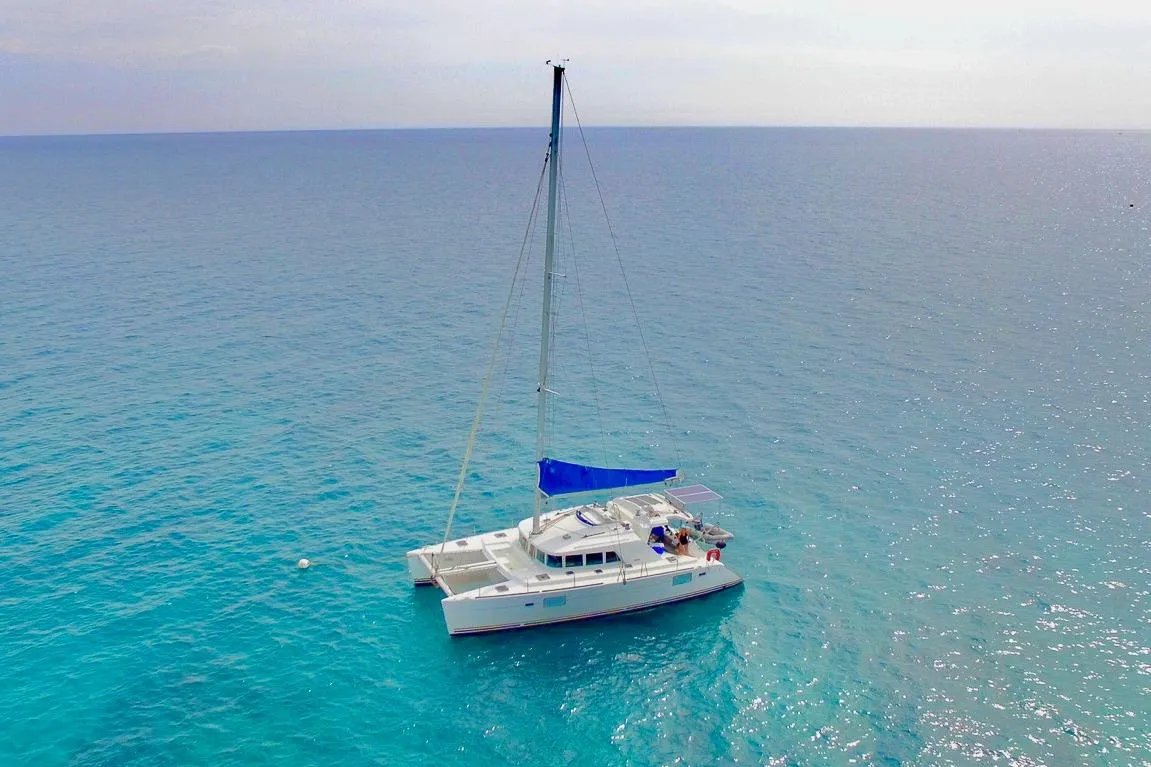 Aerial view of a 2005 Lagoon 440 catamaran sailing on clear blue ocean waters.
