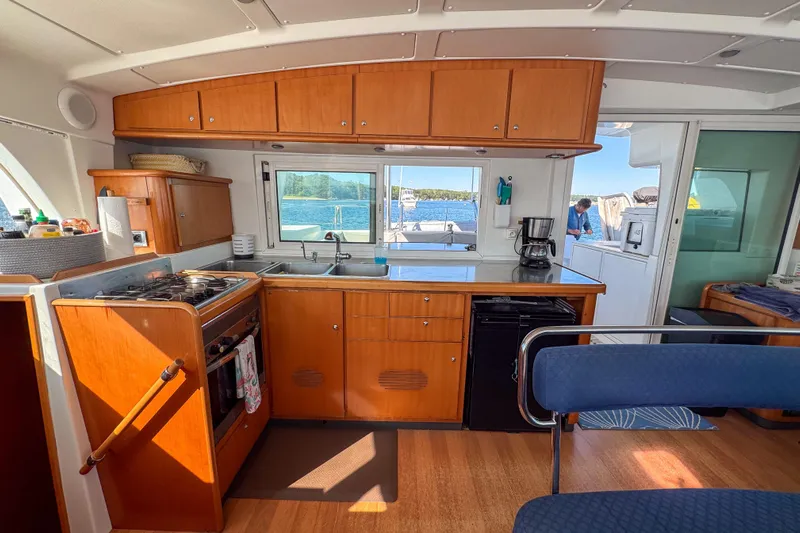 Liberty Yacht Photos Pics Interior of 2005 Lagoon 440 catamaran kitchen with wooden cabinets and ocean view.