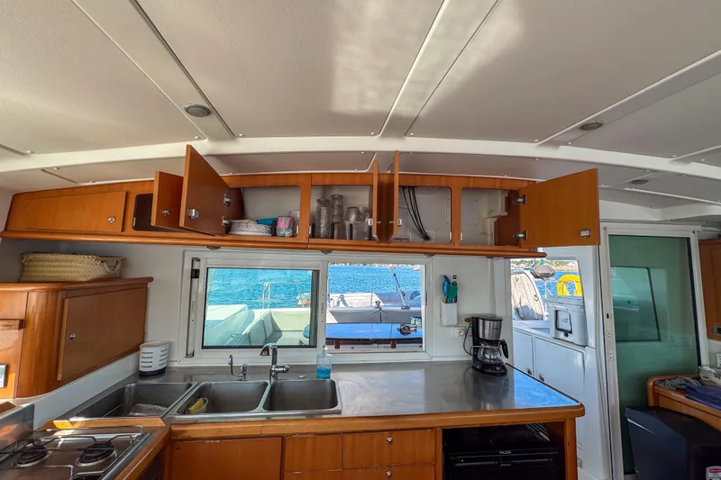 Liberty Yacht Photos Pics Interior of 2005 Lagoon 440 catamaran kitchen with open cabinets and ocean view.