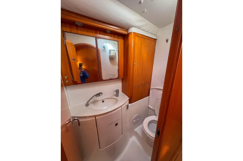 Liberty Yacht Photos Pics Bathroom interior of 2005 Lagoon 440 yacht, featuring wooden cabinetry and compact design.