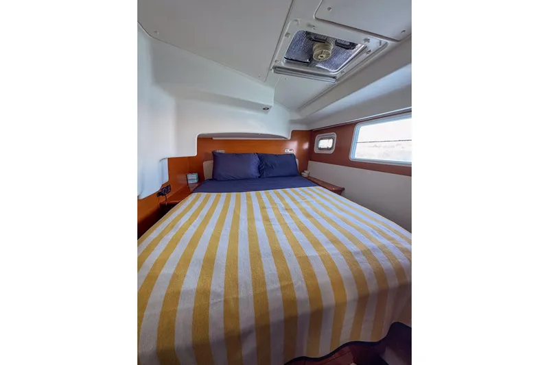 Liberty Yacht Photos Pics Cozy bedroom interior of 2005 Lagoon 440 yacht with striped bedding and porthole window.