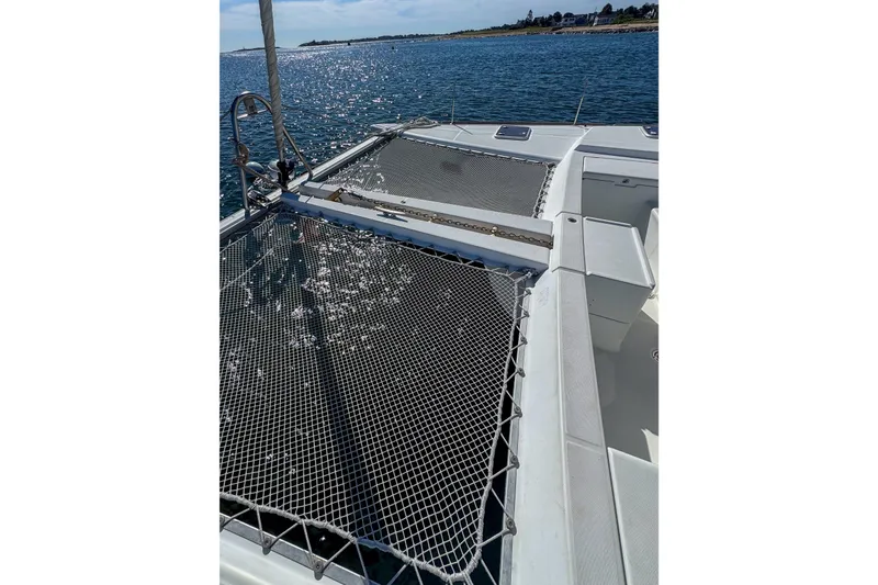 Liberty Yacht Photos Pics 2005 Lagoon 440 catamaran deck with netting over water, sunny day.