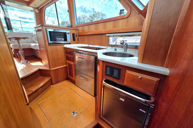  Yacht Photos Pics 2017 Sabre 42 Salon Express yacht kitchen with wood cabinetry, stainless appliances, and large windows.