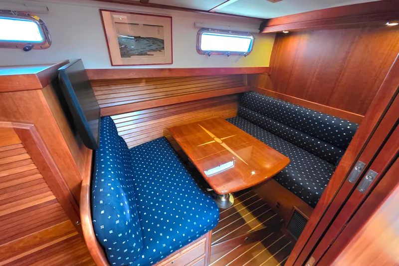  Yacht Photos Pics Interior of 2017 Sabre 42 Salon Express with wooden dining area and blue cushioned seating.