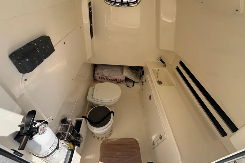  Yacht Photos Pics 2021 Boston Whaler 330 Outrage cabin interior with toilet, sink, and safety gear.