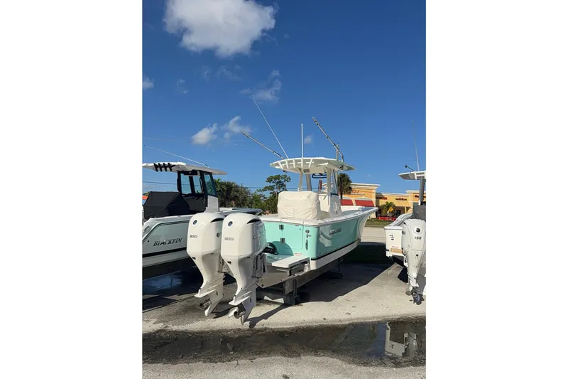 28-563 Brokerage Higgins Yacht Photos Pics 2021 Regulator 28 boat with twin engines, parked outdoors under a clear blue sky.