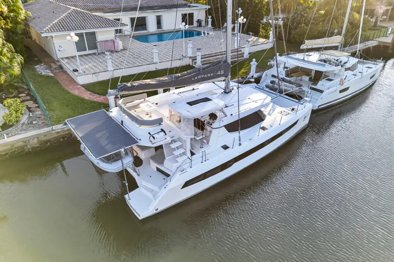  Yacht Photos Pics Aerial view of a 2022 Leopard 45 catamaran docked near a waterfront home.