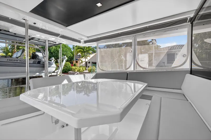  Yacht Photos Pics Interior of 2022 Leopard 45 catamaran with sleek seating and table, docked near lush greenery.