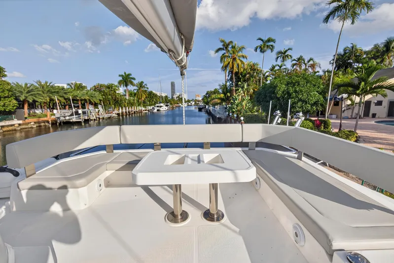  Yacht Photos Pics Luxurious 2022 Leopard 45 yacht deck with seating, overlooking a scenic canal and palm trees.