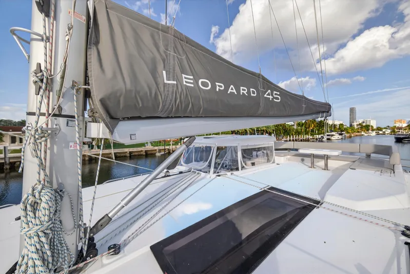  Yacht Photos Pics 2022 Leopard 45 catamaran with sails docked in a marina under a blue sky.