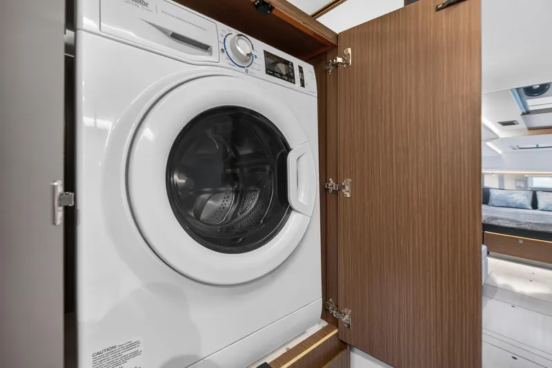  Yacht Photos Pics Washing machine in a Leopard 45 yacht, 2022 model, with wooden cabinet door open.