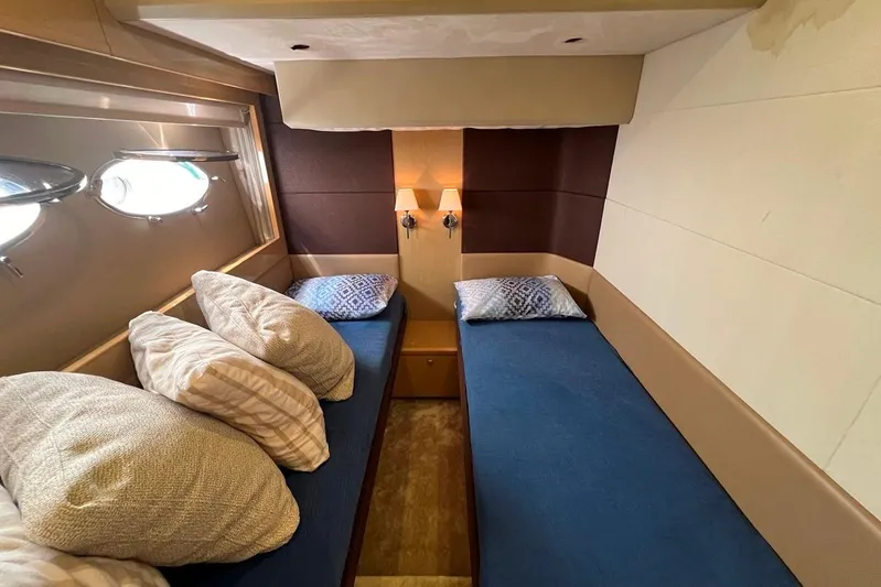  Yacht Photos Pics Cozy twin cabin in 2010 Princess V62 yacht with blue bedding and porthole windows.