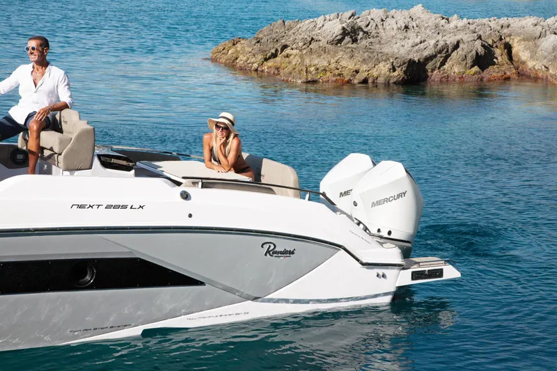  Yacht Photos Pics 2025 Ranieri NEXT 285 XL boat cruising in clear blue waters near rocky shore.
