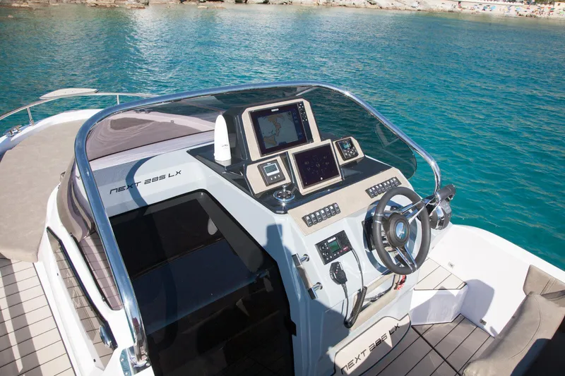  Yacht Photos Pics 2025 Ranieri NEXT 285 XL boat dashboard with modern navigation equipment on clear blue water.