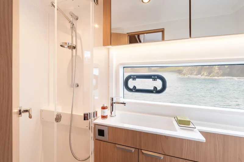 Tbd Yacht Photos Pics Modern yacht bathroom with shower, wooden cabinetry, and ocean view window in Bali CATSMART 2026 model.
