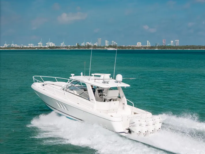  Yacht Photos Pics 2009 Intrepid 475 Sport Yacht cruising on turquoise waters, city skyline in background.
