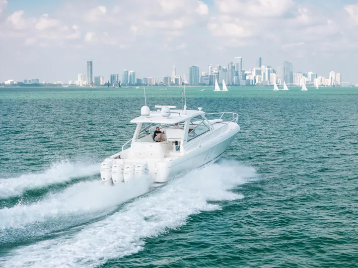  Yacht Photos Pics 2009 Intrepid 475 Sport Yacht cruising on ocean with city skyline in background.