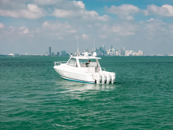  Yacht Photos Pics 2009 Intrepid 475 Sport Yacht cruising on open water with city skyline backdrop.