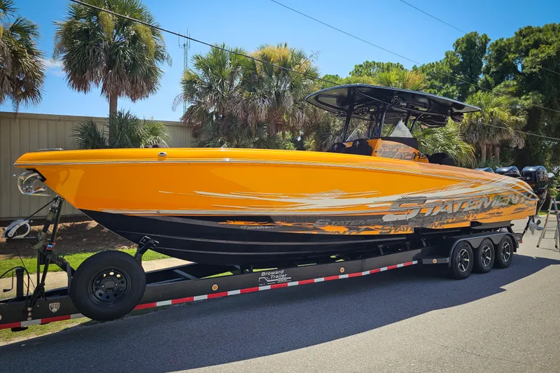  Yacht Photos Pics Bright orange 2016 Statement 380 Open boat on trailer, surrounded by palm trees.