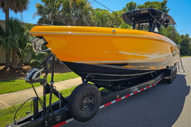  Yacht Photos Pics 2016 Statement 380 Open boat in vibrant orange on a trailer, surrounded by palm trees.