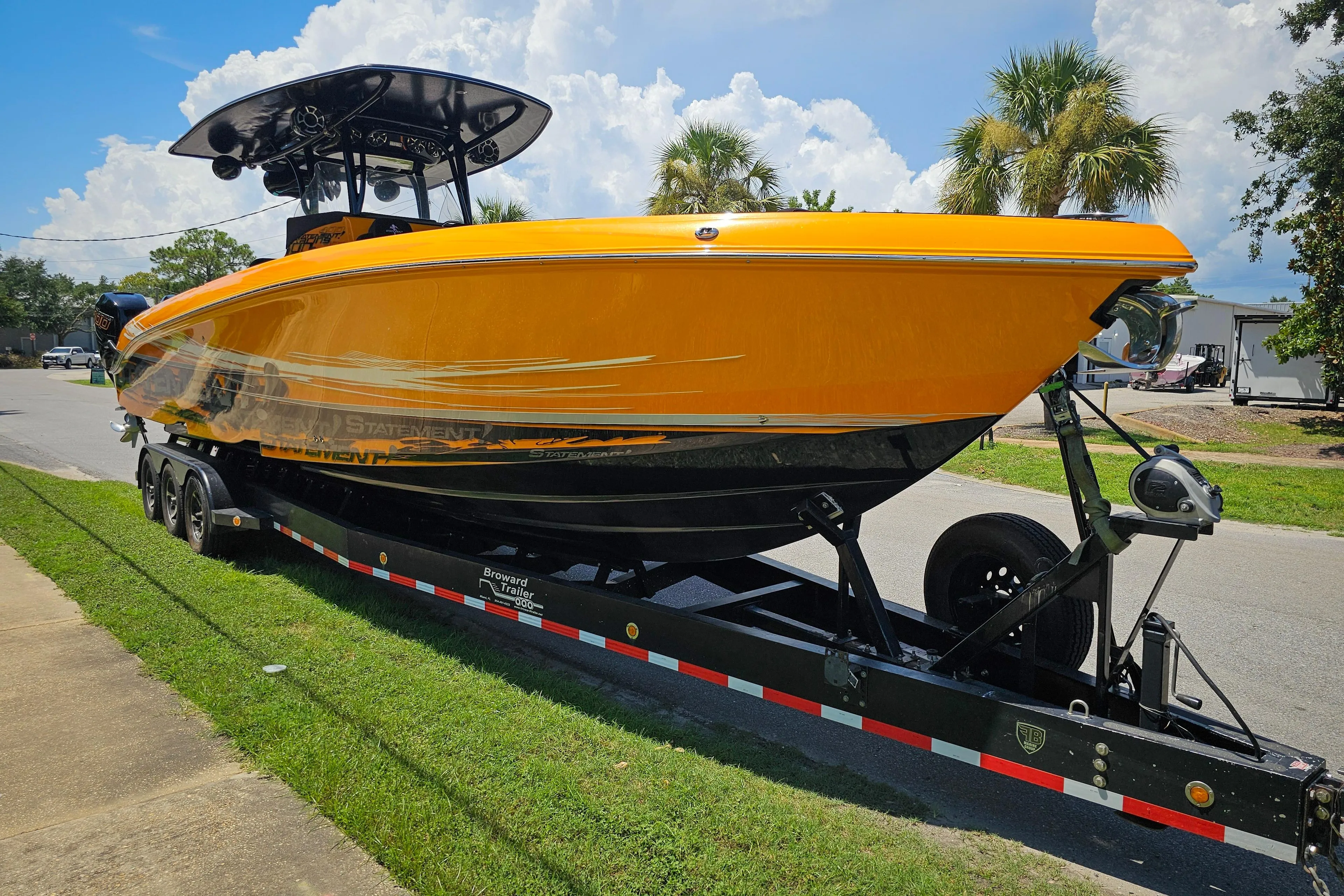 Bright orange 2016 Statement 380 Open boat on a trailer, parked on a sunny street.