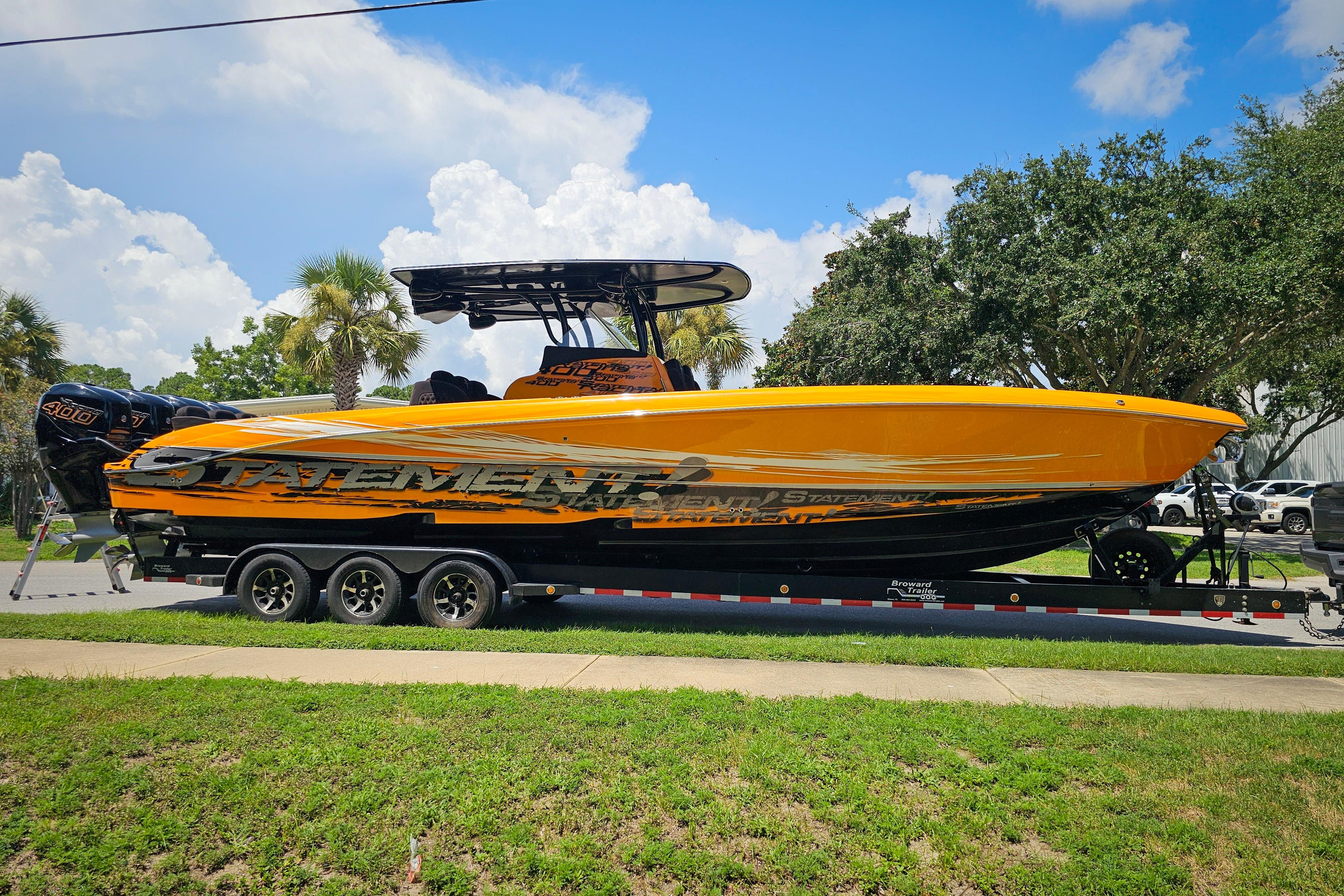 2016 Statement 380 Open boat on trailer, vibrant orange design, parked outdoors under blue sky.
