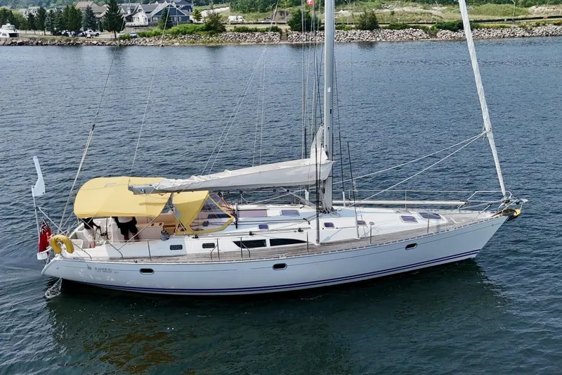 Free Spirits Yacht Photos Pics Jeanneau Sun Odyssey 45.2 sailboat, 2000 model, cruising on calm waters with yellow canopy.