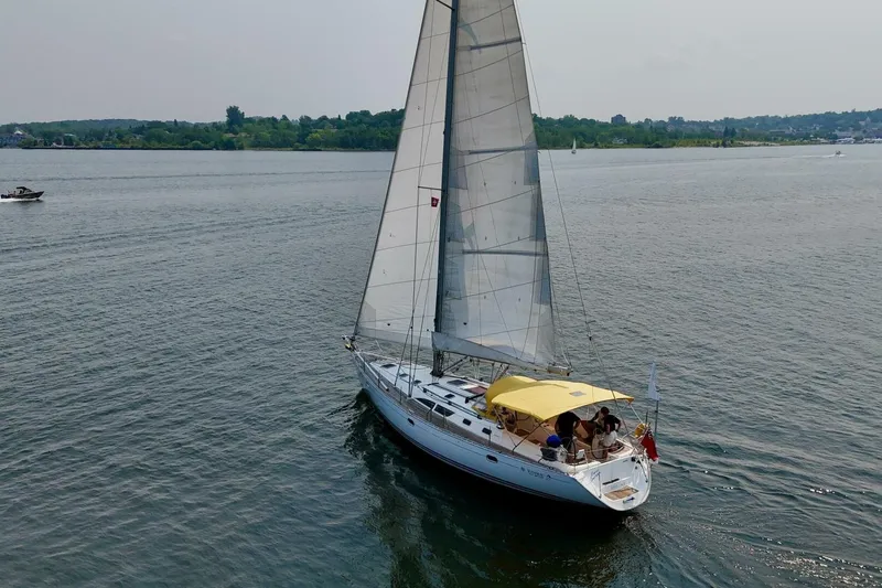 Free Spirits Yacht Photos Pics Jeanneau Sun Odyssey 45.2 sailing on calm waters, 2000 model, with yellow canopy.