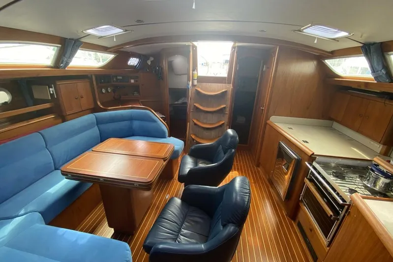 Free Spirits Yacht Photos Pics Interior of 2000 Jeanneau Sun Odyssey 45.2 yacht with blue seating and wooden finishes.