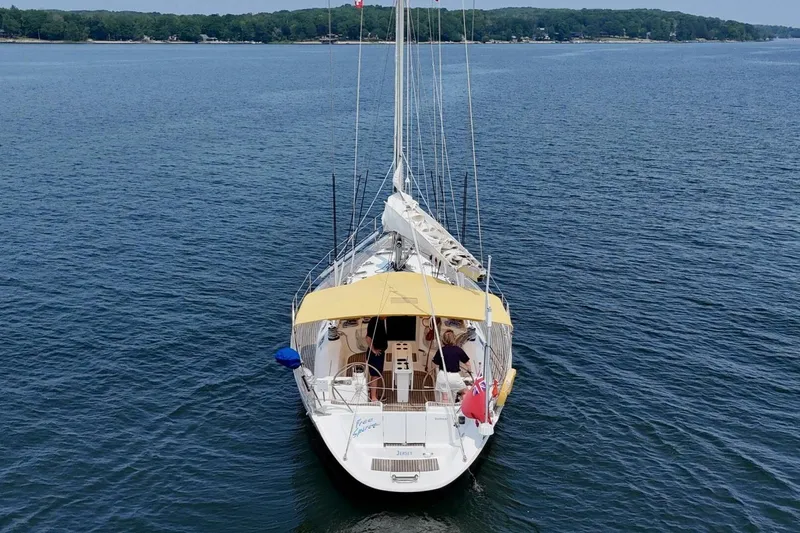 Free Spirits Yacht Photos Pics Jeanneau Sun Odyssey 45.2 sailboat on calm water, 2000 model, with yellow canopy.