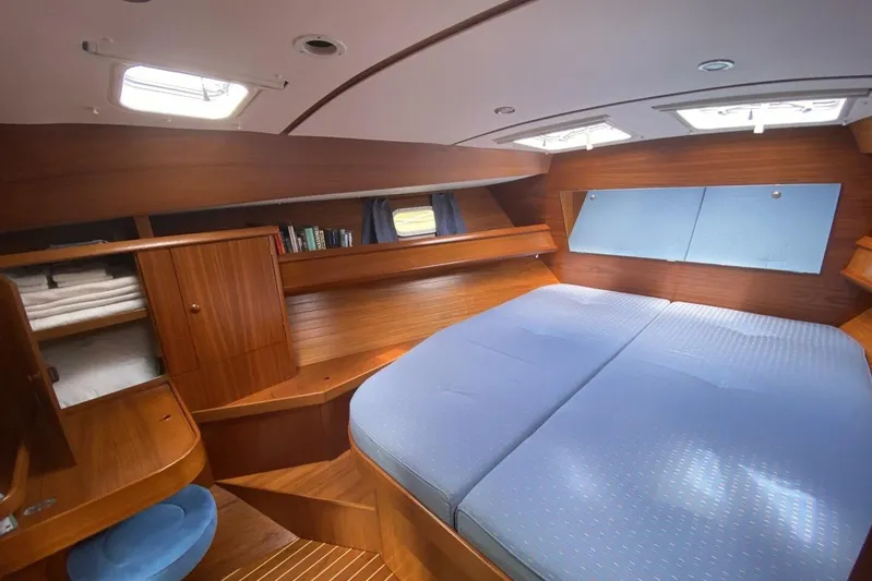 Free Spirits Yacht Photos Pics Cozy cabin interior of 2000 Jeanneau Sun Odyssey 45.2 with wood finish and blue bedding.