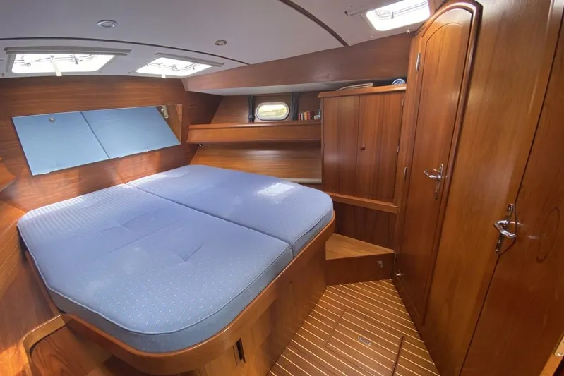 Free Spirits Yacht Photos Pics Cozy cabin interior of 2000 Jeanneau Sun Odyssey 45.2 with wooden finish and blue bedding.