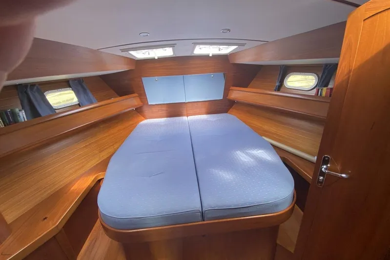 Free Spirits Yacht Photos Pics Interior cabin of 2000 Jeanneau Sun Odyssey 45.2 with wooden finish and blue bedding.