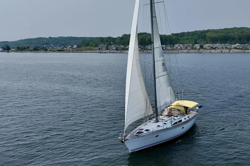 Free Spirits Yacht Photos Pics Sailing yacht Jeanneau Sun Odyssey 45.2, 2000 model, cruising on calm waters near a coastal town.