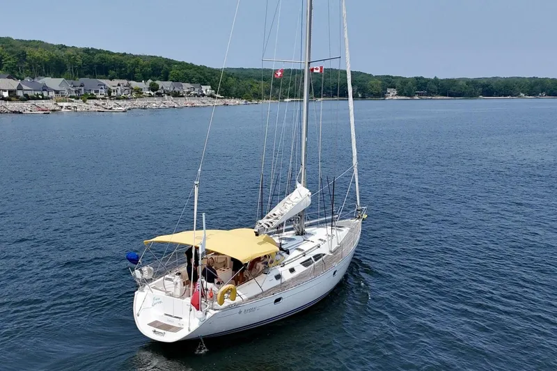 Free Spirits Yacht Photos Pics Jeanneau Sun Odyssey 45.2 sailboat from 2000 on calm waters near a coastal town.