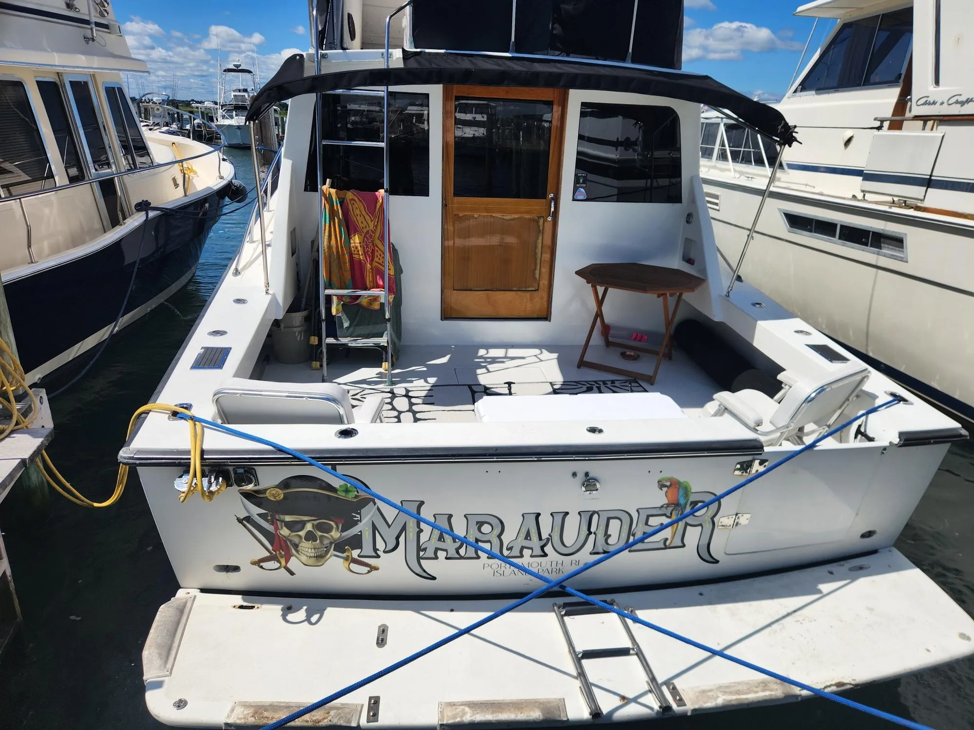 1977 Pacemaker 40 Sportfisherman boat named "Marauder" docked at marina, rear view.