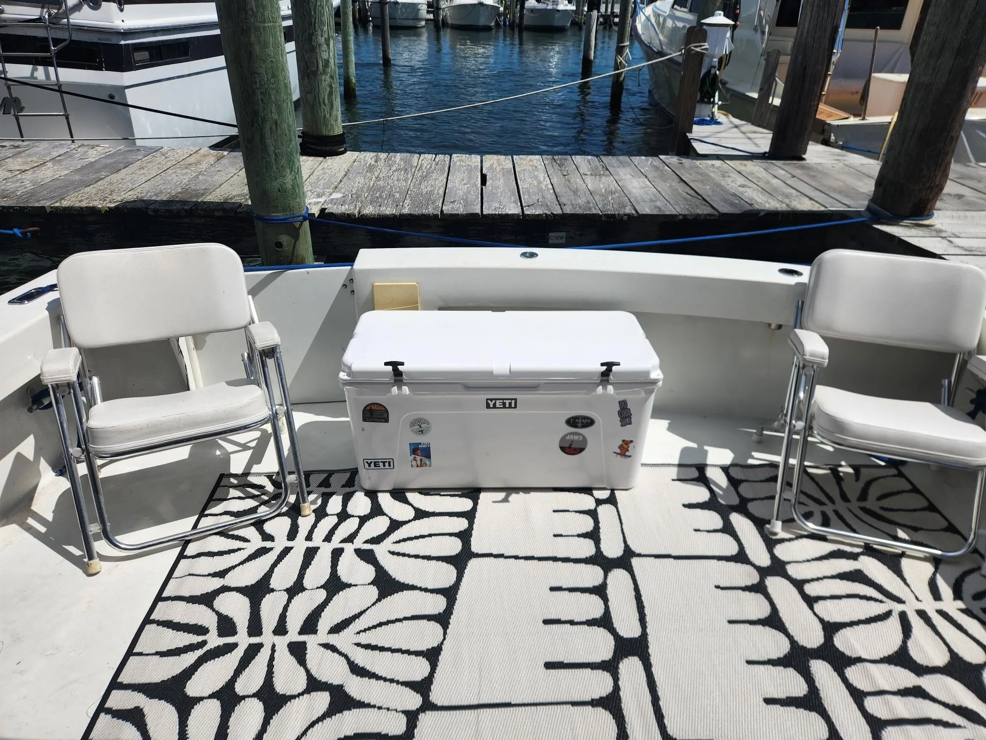 1977 Pacemaker 40 Sportfisherman boat deck with chairs, cooler, and patterned rug at marina.