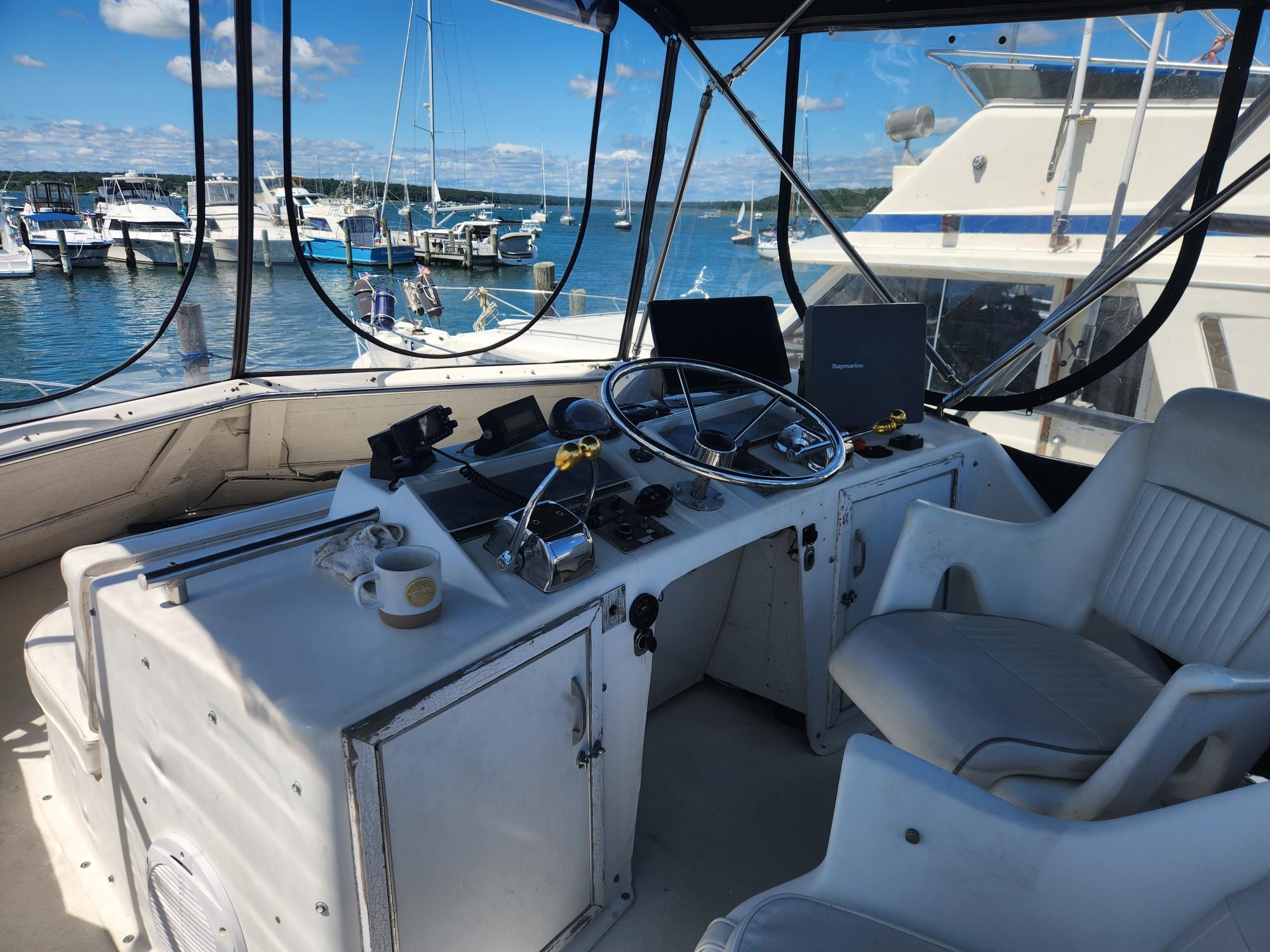 1977 Pacemaker 40 Sportfisherman helm with steering wheel, controls, and marina view.