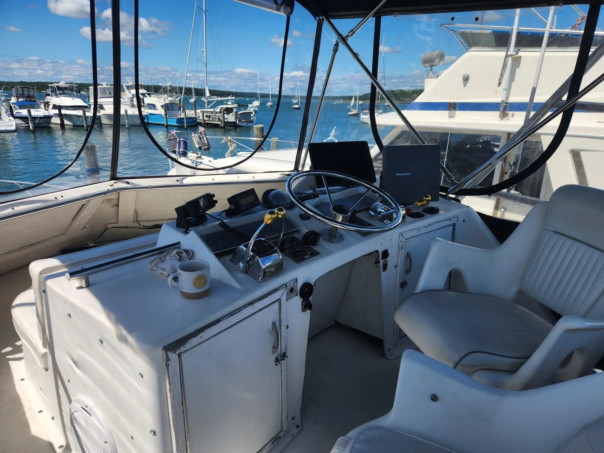 1977 Pacemaker 40 Sportfisherman helm with steering wheel, controls, and marina view.