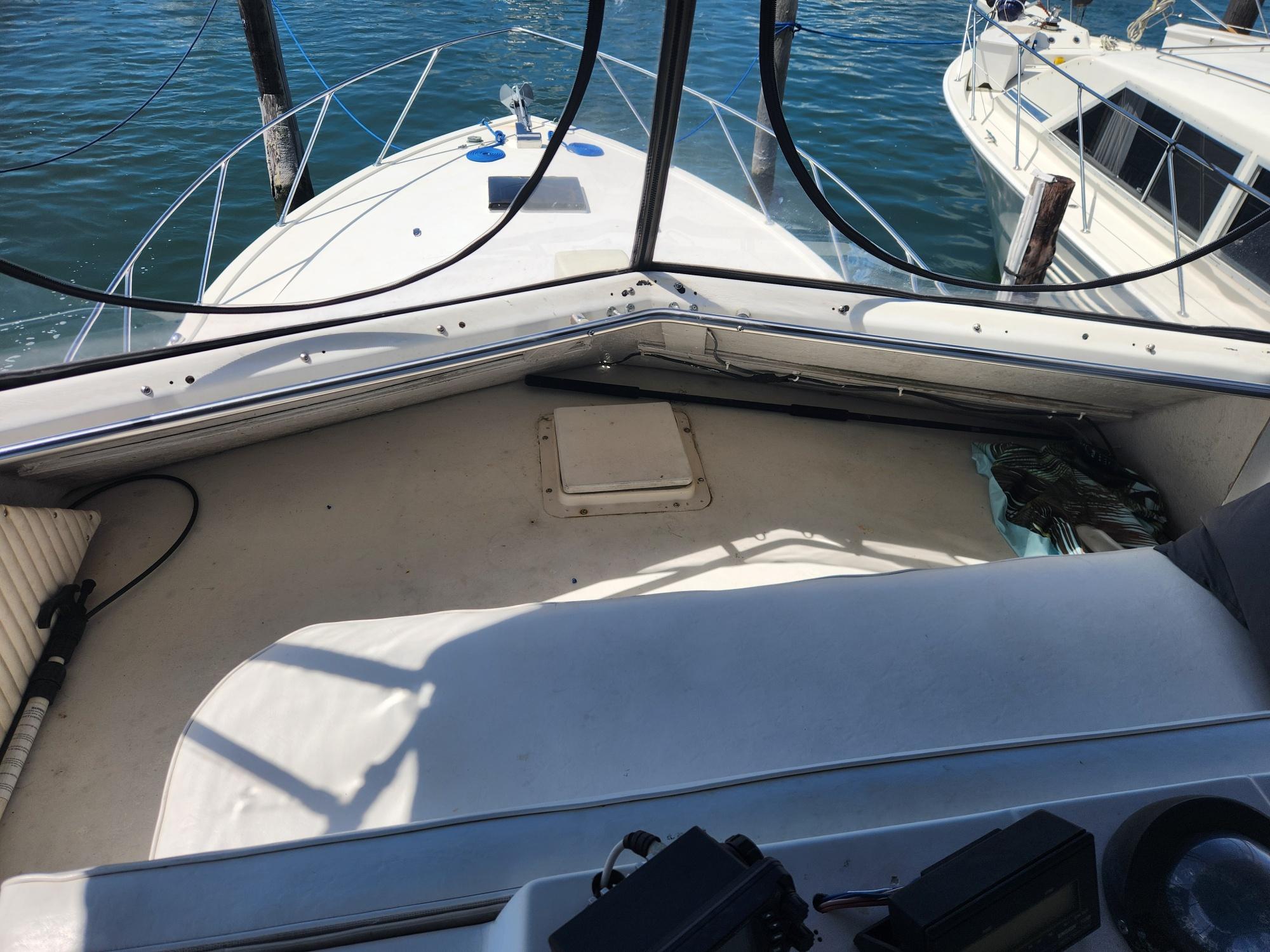 1977 Pacemaker 40 Sportfisherman boat deck with railing, docked beside another vessel.