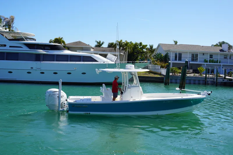  Yacht Photos Pics 2024 Regulator 26XO boat cruising in a sunny marina with luxury yachts nearby.