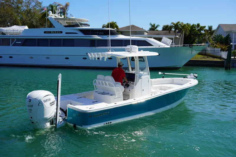  Yacht Photos Pics 2024 Regulator 26XO boat cruising in clear turquoise water near a large yacht.