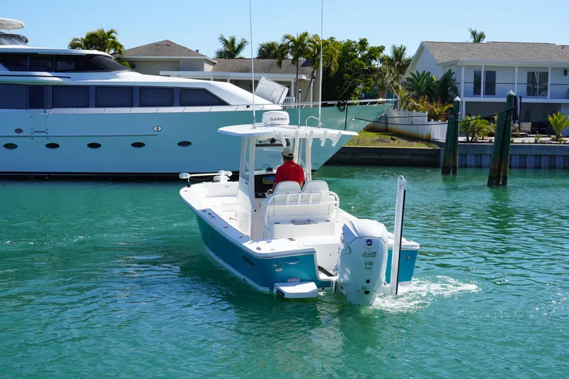  Yacht Photos Pics 2024 Regulator 26XO boat cruising in a sunny marina with waterfront homes.